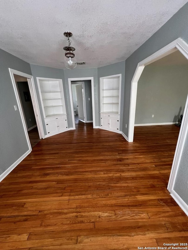 interior space featuring dark hardwood / wood-style flooring, built in features, and a textured ceiling