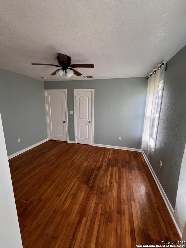 empty room featuring ceiling fan, wood-type flooring, and a textured ceiling