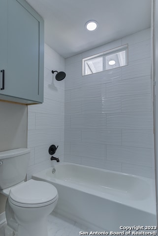 bathroom with tile floors, toilet, and tiled shower / bath