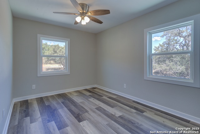 unfurnished room with dark hardwood / wood-style flooring, ceiling fan, and a wealth of natural light