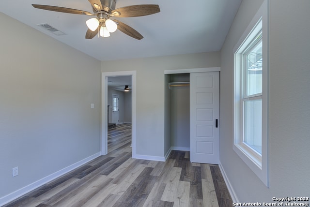 unfurnished bedroom with ceiling fan, a closet, and dark wood-type flooring