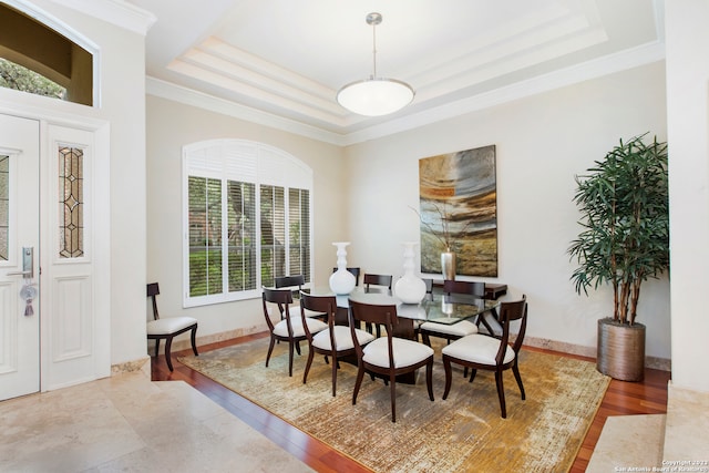 dining space featuring wood-type flooring, a raised ceiling, and ornamental molding