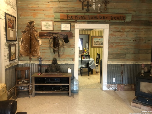 interior space with light tile flooring, wooden walls, and a wood stove