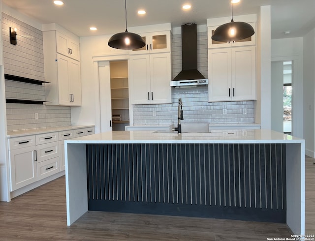 kitchen with pendant lighting, wall chimney range hood, tasteful backsplash, white cabinetry, and dark hardwood / wood-style flooring