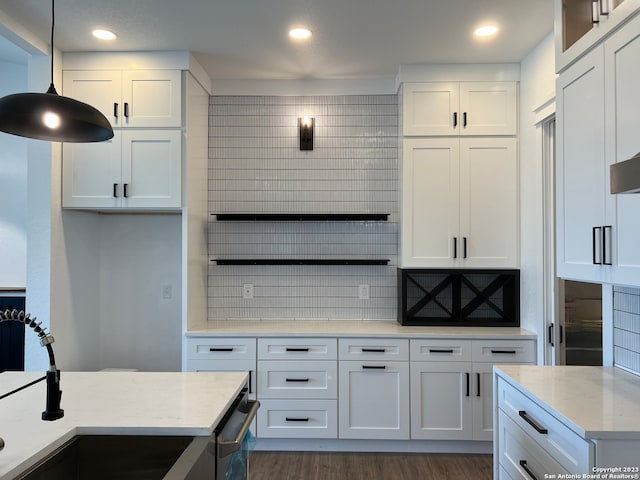 kitchen featuring hanging light fixtures, dark wood-type flooring, white cabinets, light stone counters, and tasteful backsplash