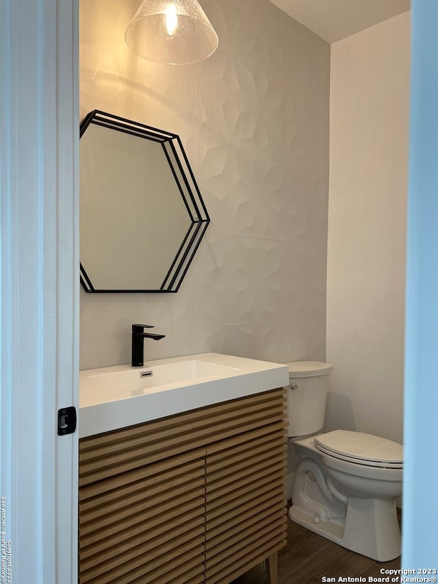 bathroom with toilet, hardwood / wood-style floors, and vanity