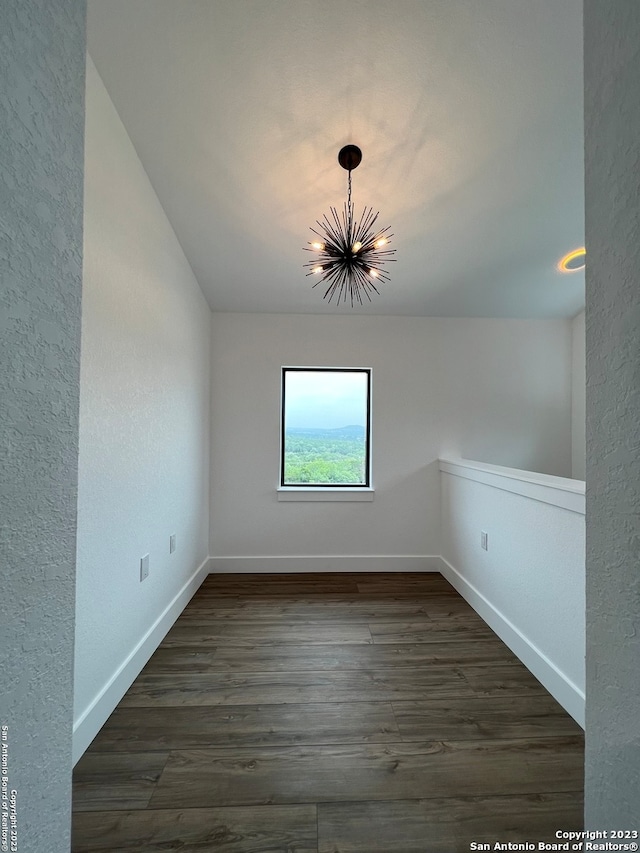 spare room featuring an inviting chandelier and dark hardwood / wood-style flooring