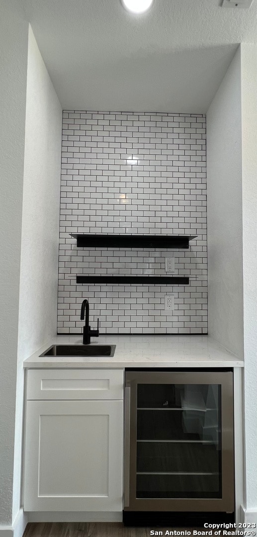 bar featuring sink, white cabinets, dark wood-type flooring, and beverage cooler