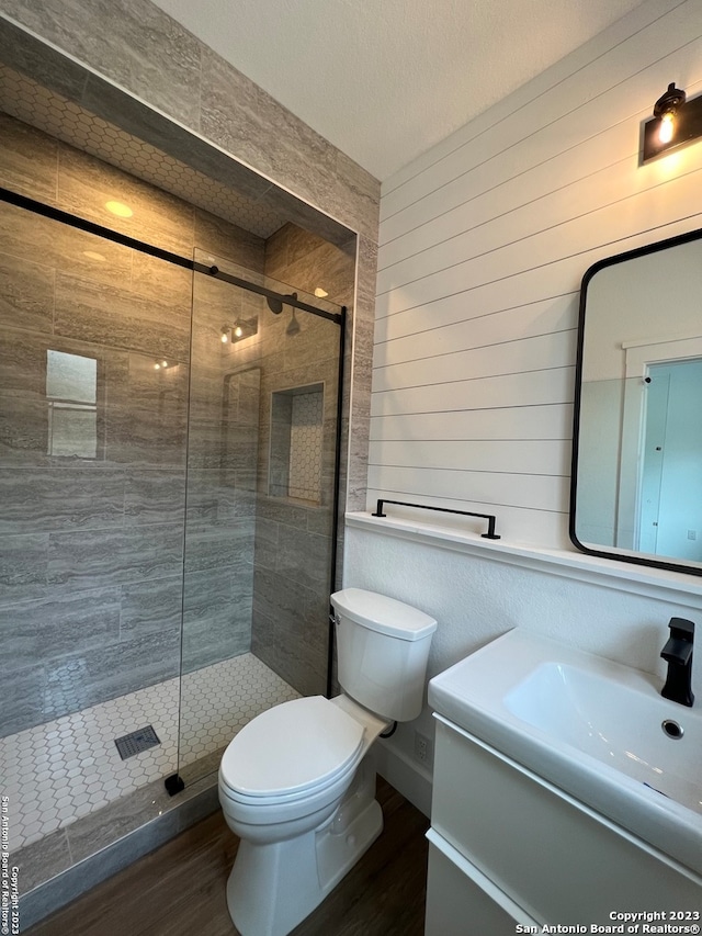 bathroom featuring toilet, a textured ceiling, vanity, walk in shower, and wood-type flooring