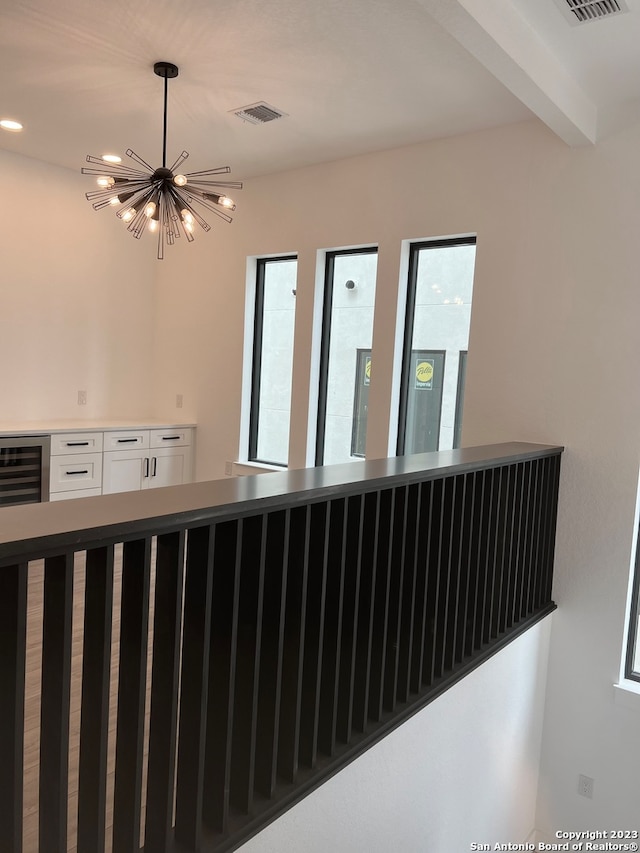 interior space featuring wine cooler, a notable chandelier, and beam ceiling