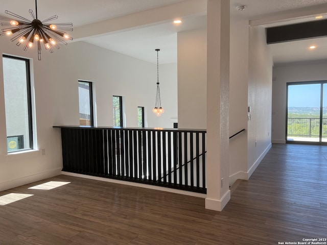 spare room with dark wood-type flooring, an inviting chandelier, and beamed ceiling