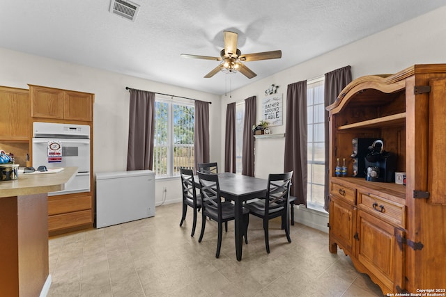 dining room featuring ceiling fan, light tile floors, and a textured ceiling