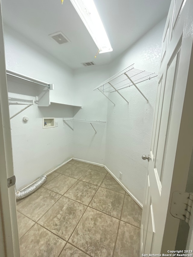 walk in closet with light tile floors