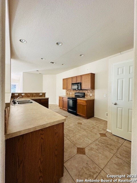 kitchen with electric stove, light tile flooring, a textured ceiling, tasteful backsplash, and sink