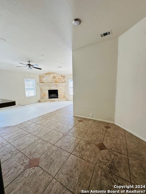 unfurnished living room featuring ceiling fan, a textured ceiling, and tile floors