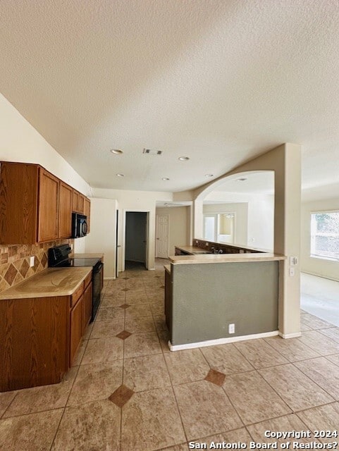 kitchen with light tile floors, a textured ceiling, black range with electric stovetop, and tasteful backsplash