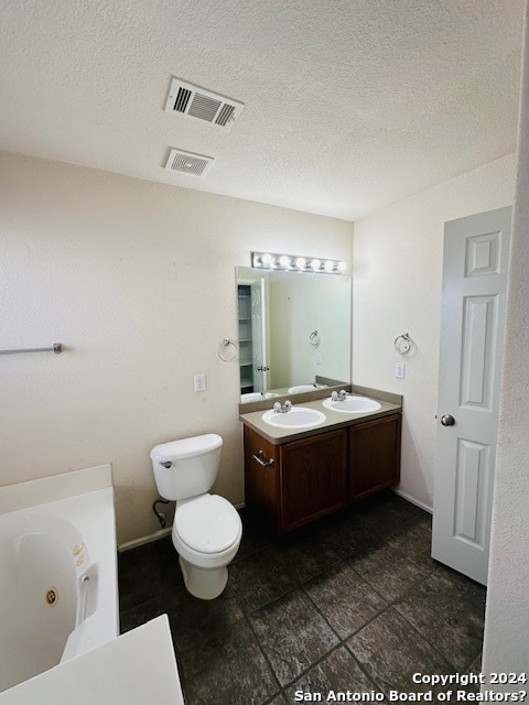 bathroom featuring tile flooring, toilet, double vanity, and a textured ceiling