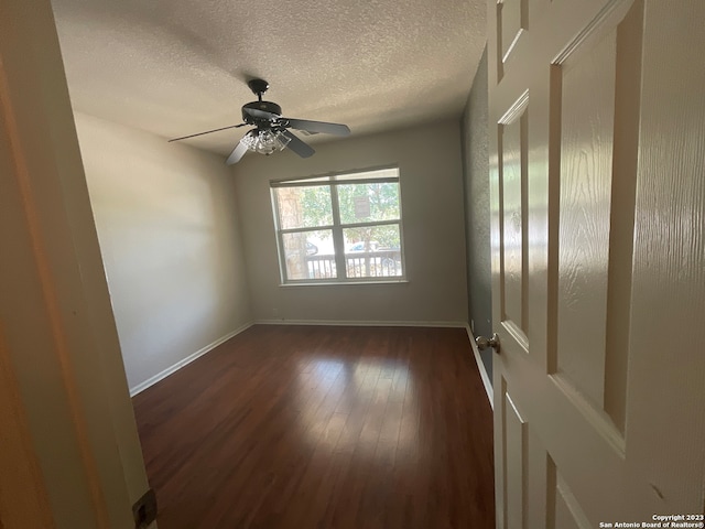 empty room with ceiling fan, a textured ceiling, and dark hardwood / wood-style flooring