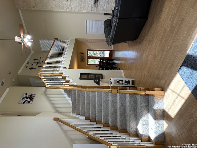 stairway featuring ceiling fan and a high ceiling