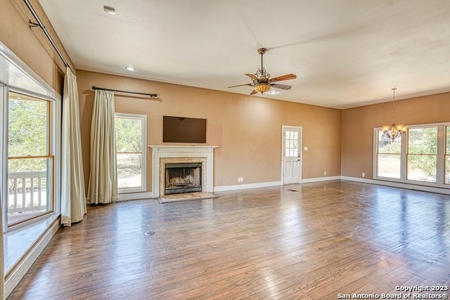 unfurnished living room featuring ceiling fan with notable chandelier, dark hardwood / wood-style floors, and a fireplace