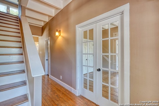 stairway with french doors and light wood-type flooring