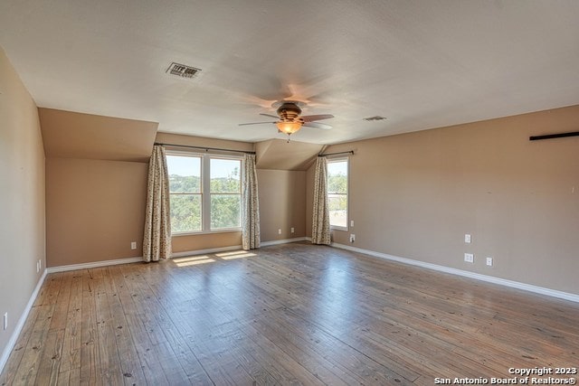 spare room featuring wood-type flooring, vaulted ceiling, and ceiling fan