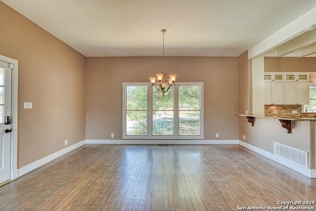 spare room with a notable chandelier and light wood-type flooring