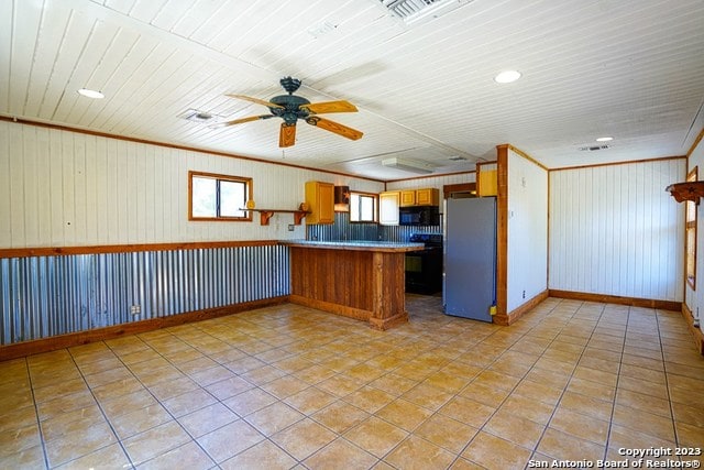 kitchen with ceiling fan, kitchen peninsula, light tile floors, and stainless steel refrigerator