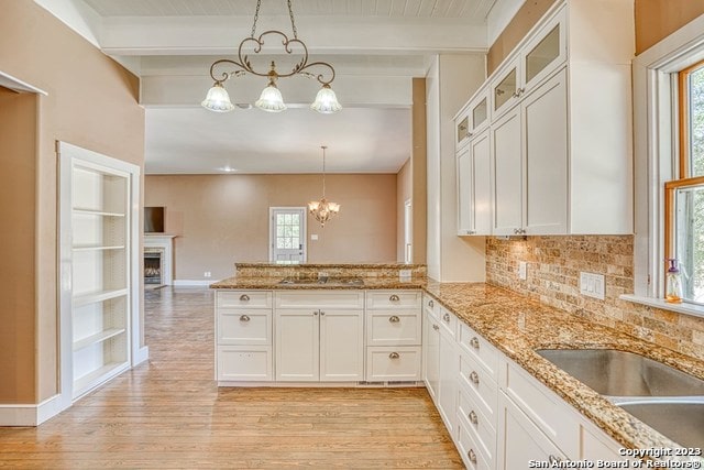 kitchen with beamed ceiling, a notable chandelier, and a healthy amount of sunlight