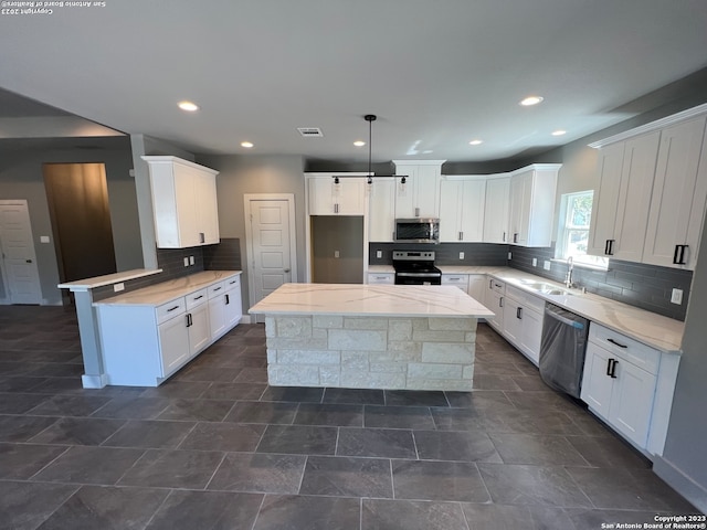 kitchen with decorative light fixtures, light stone countertops, tasteful backsplash, appliances with stainless steel finishes, and white cabinetry