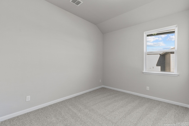 carpeted spare room with vaulted ceiling