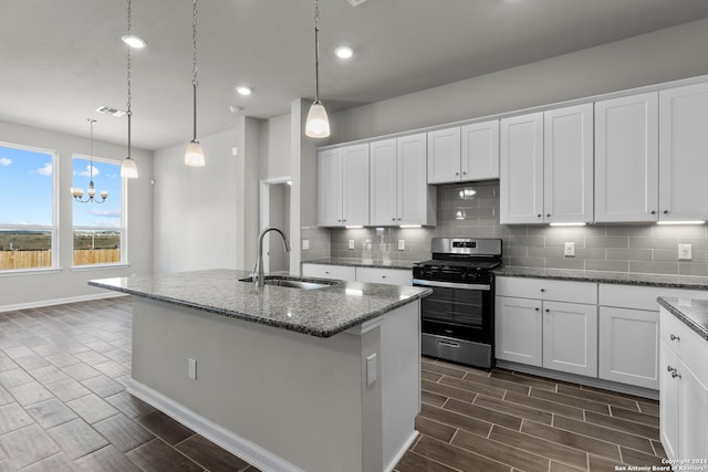 kitchen featuring stainless steel gas range, sink, white cabinetry, decorative light fixtures, and tasteful backsplash