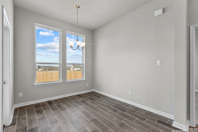 unfurnished room with a notable chandelier, a wealth of natural light, and dark hardwood / wood-style floors