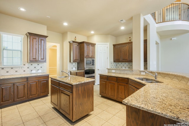 kitchen with tasteful backsplash, light tile flooring, appliances with stainless steel finishes, and sink