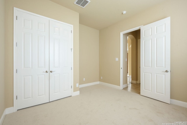 unfurnished bedroom featuring a closet and light colored carpet