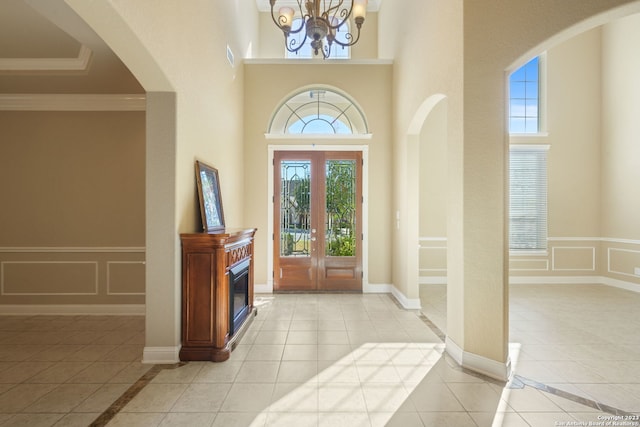 tiled entryway with a high ceiling, a notable chandelier, and french doors