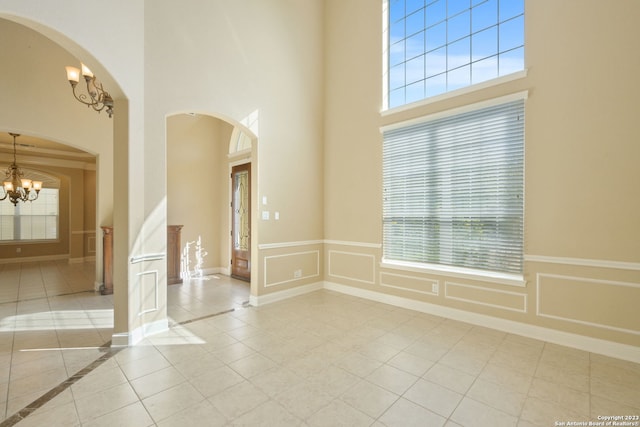 empty room with light tile floors, a chandelier, and a wealth of natural light