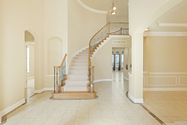 stairway featuring light tile floors and a towering ceiling