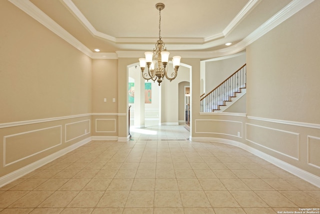 tiled empty room featuring an inviting chandelier, ornamental molding, and a tray ceiling