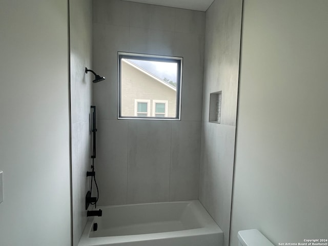 bathroom featuring toilet and tiled shower / bath