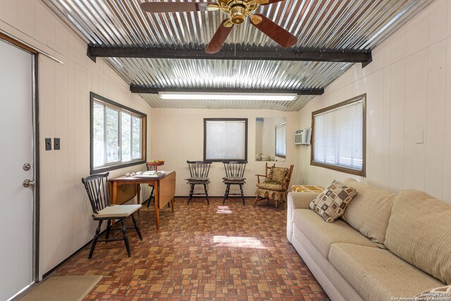 living room featuring beamed ceiling, ceiling fan, and an AC wall unit