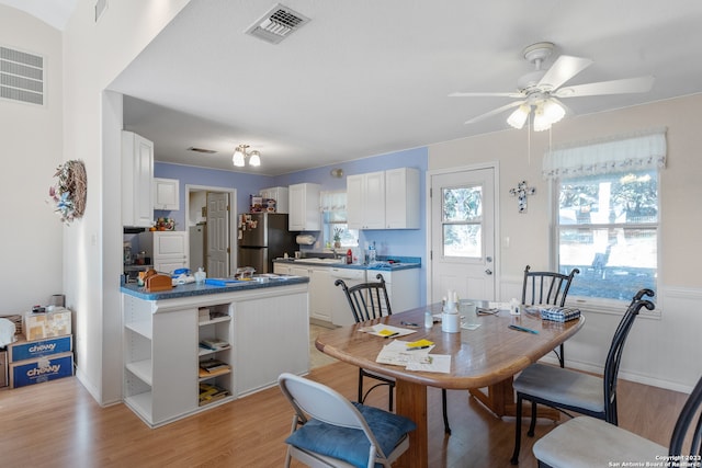 dining room featuring ceiling fan, sink, and light wood-type flooring