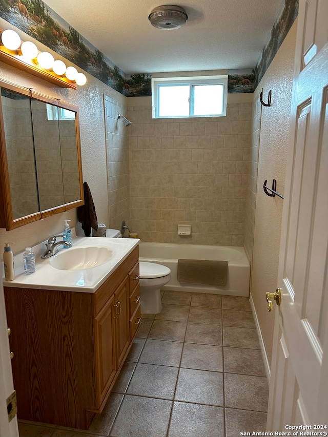 full bathroom featuring toilet, tiled shower / bath combo, a textured ceiling, vanity, and tile floors