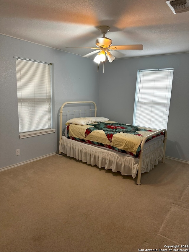 bedroom featuring ceiling fan, carpet floors, and multiple windows