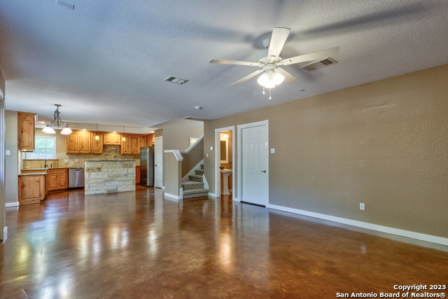 unfurnished living room with a textured ceiling and ceiling fan with notable chandelier