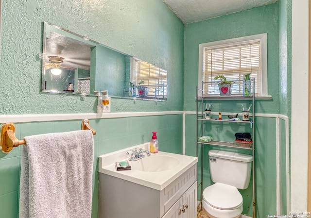 bathroom with tasteful backsplash, toilet, vanity with extensive cabinet space, a textured ceiling, and tile walls