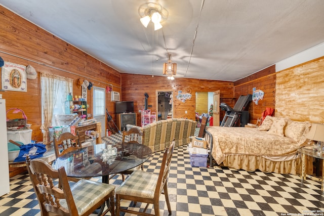 dining space featuring ceiling fan, wood walls, and light tile floors