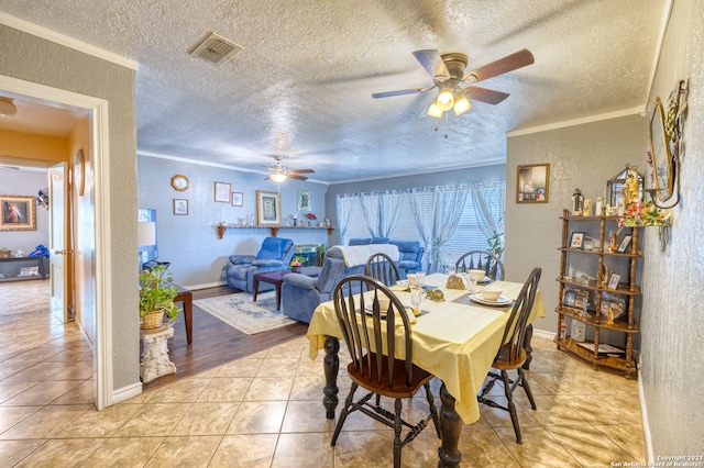 dining room with light tile floors, ornamental molding, ceiling fan, and a textured ceiling