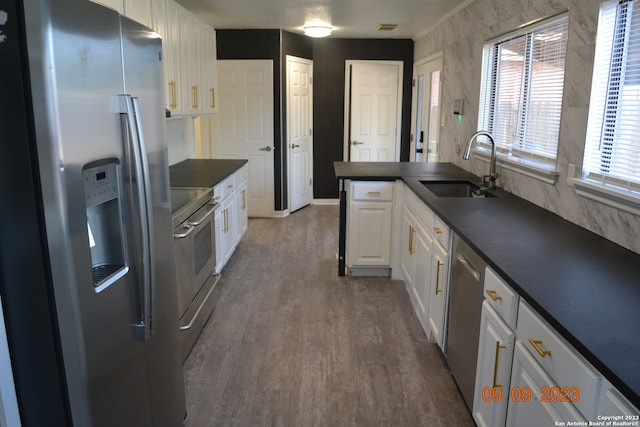 kitchen featuring hardwood / wood-style flooring, appliances with stainless steel finishes, white cabinets, and sink