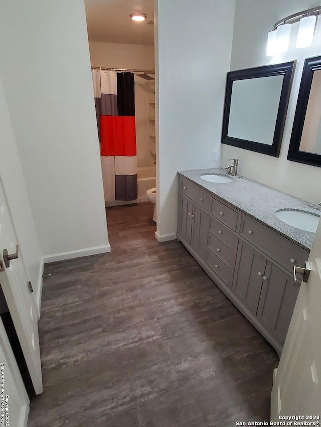 full bathroom featuring double sink vanity, toilet, shower / tub combo, and hardwood / wood-style flooring